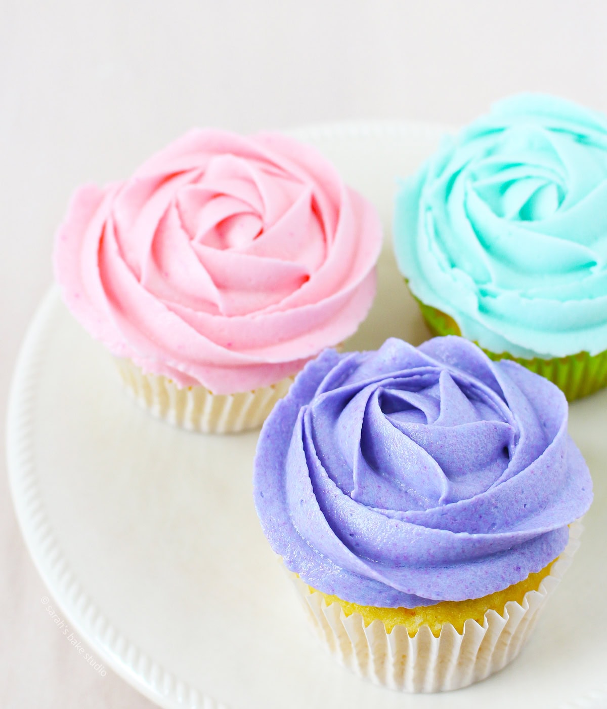 A plate with three rose frosted cupcakes.