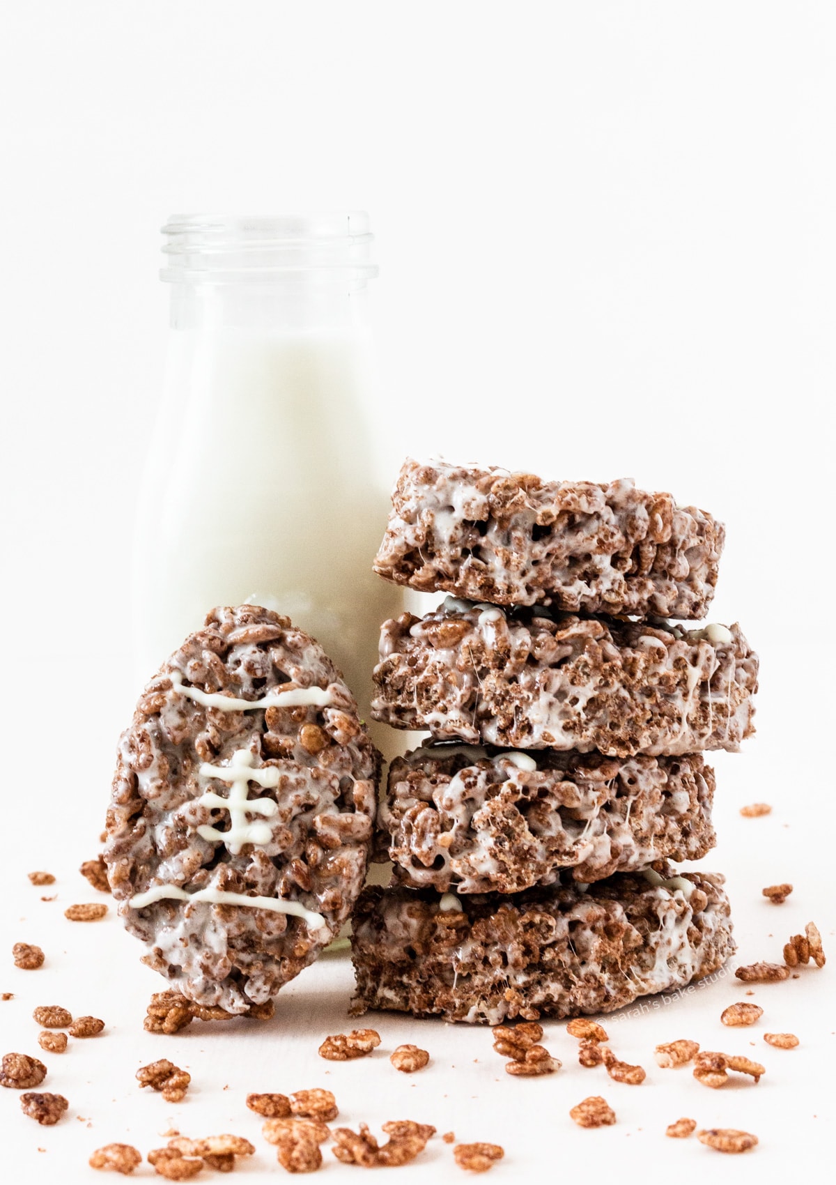 A glass of milk and a stacked tower of Football Chocolate Rice Krispies Treats.