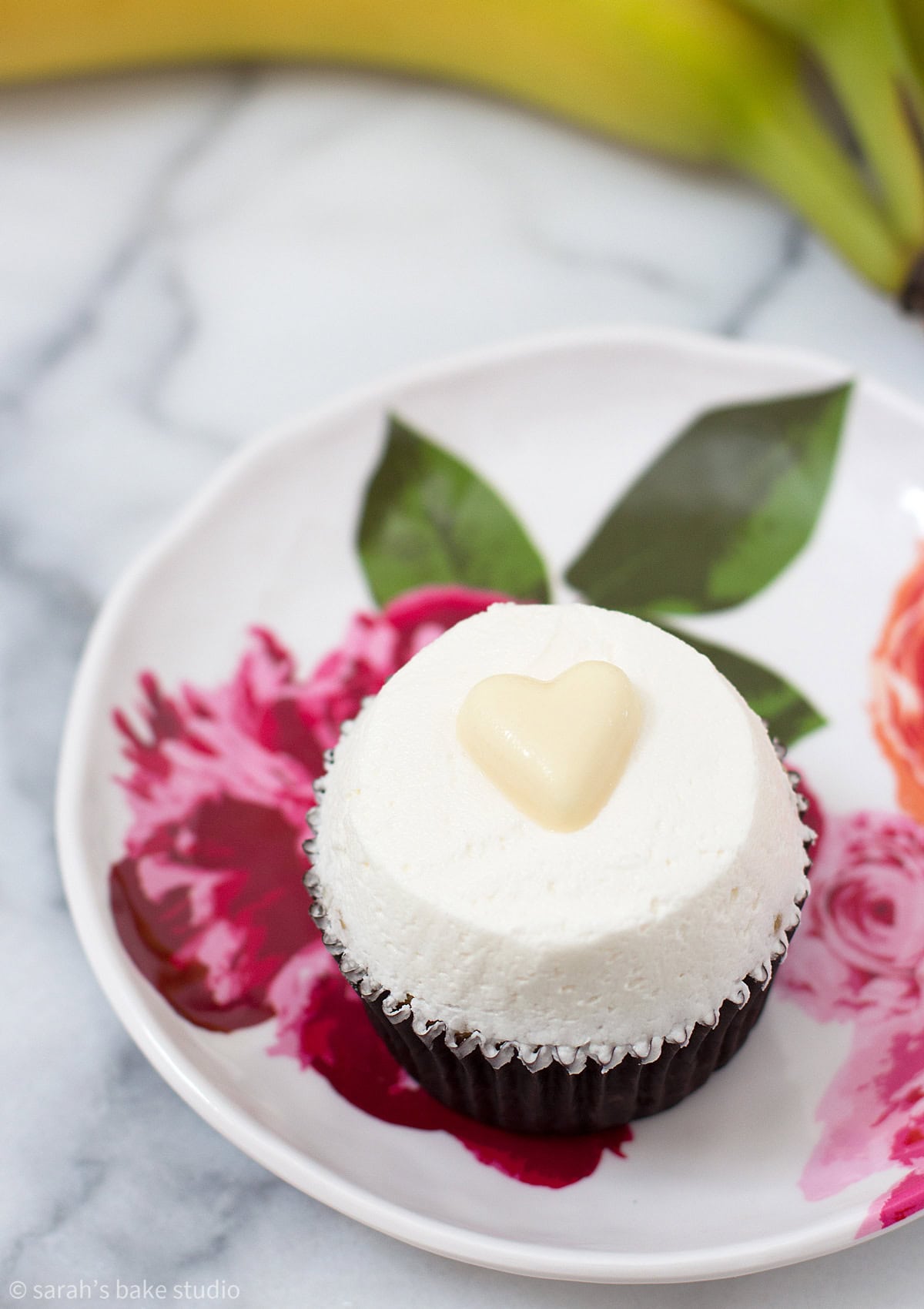A plate with a Very Banana Cupcake on it, and a bunch of bananas.