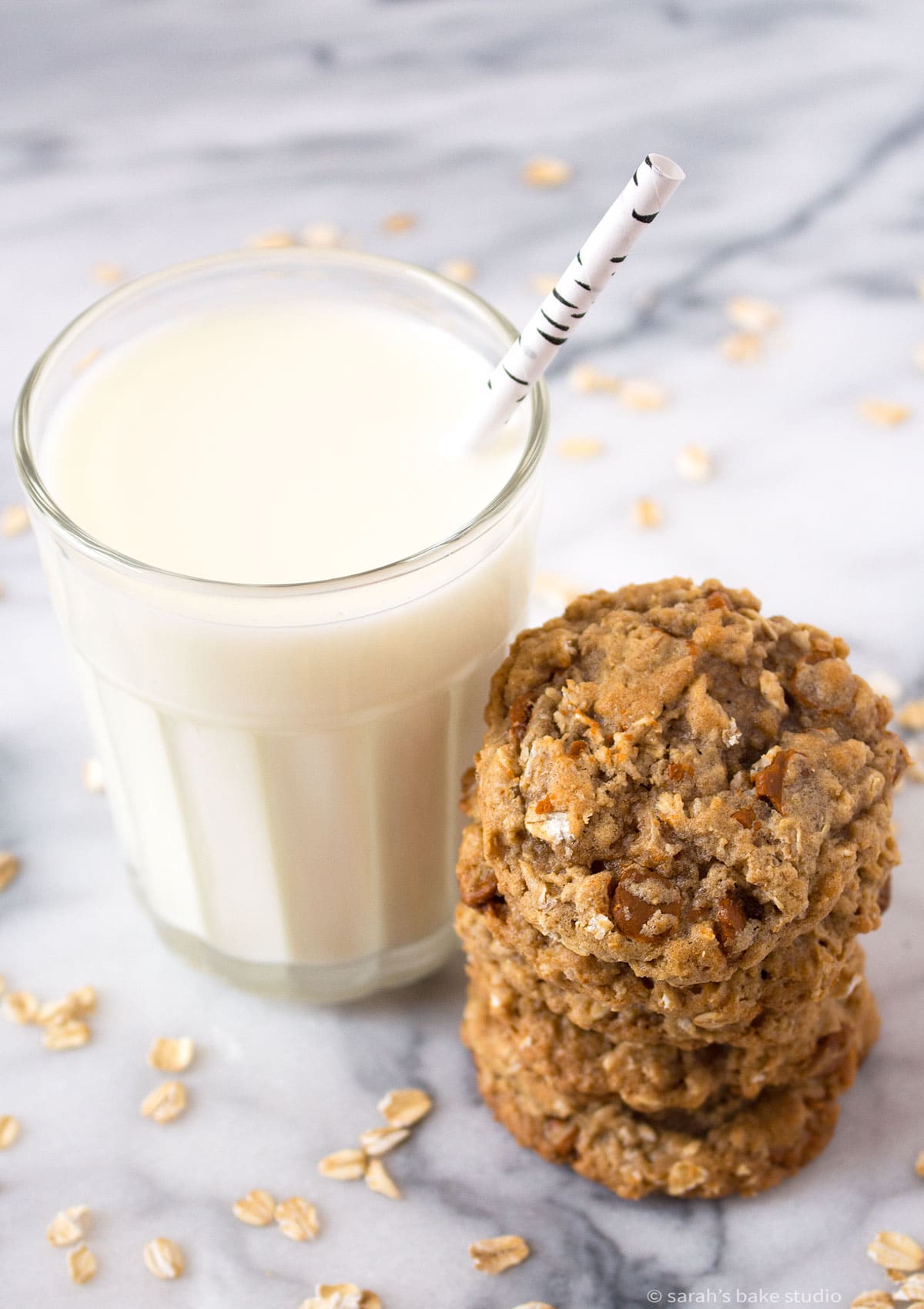 a glass of milk and a stack of oatmeal cinnamon chip cookies