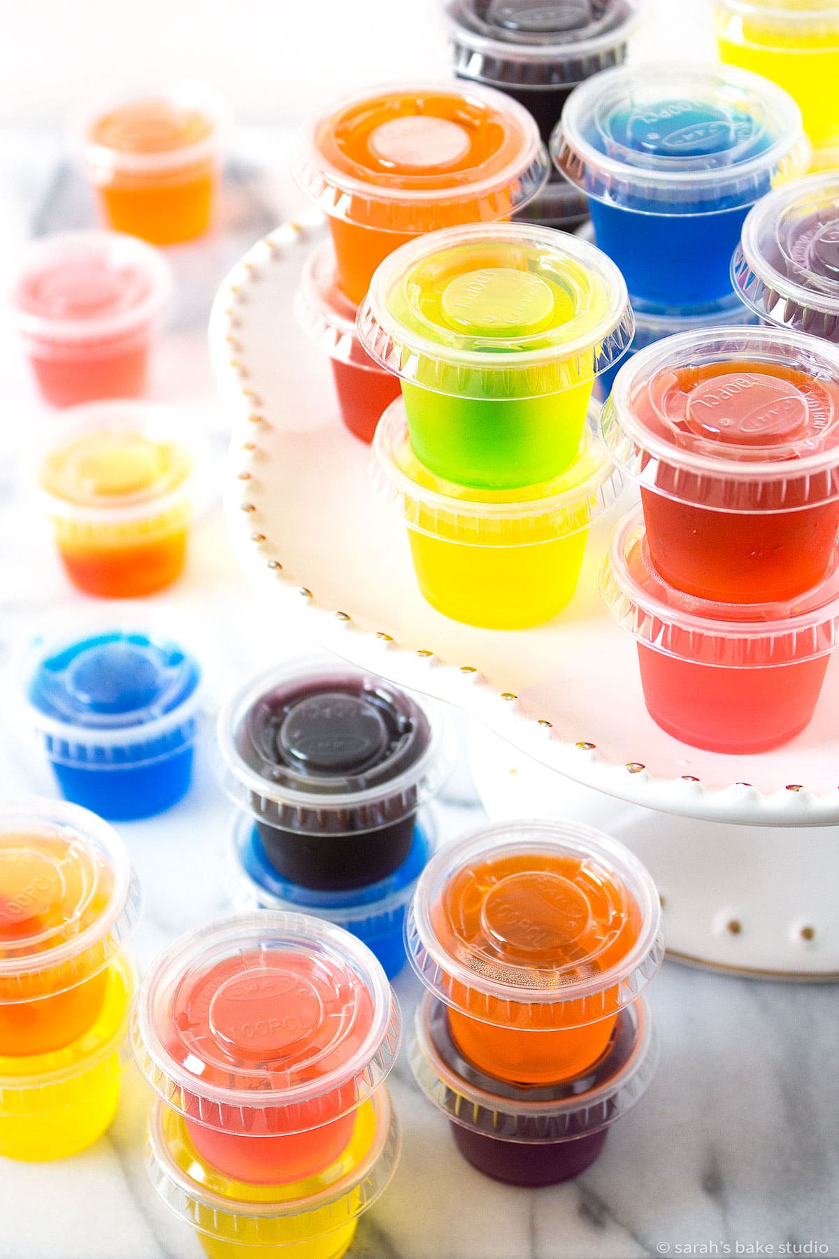 9 sensational summer jello shots in one-ounce cups on a cake stand