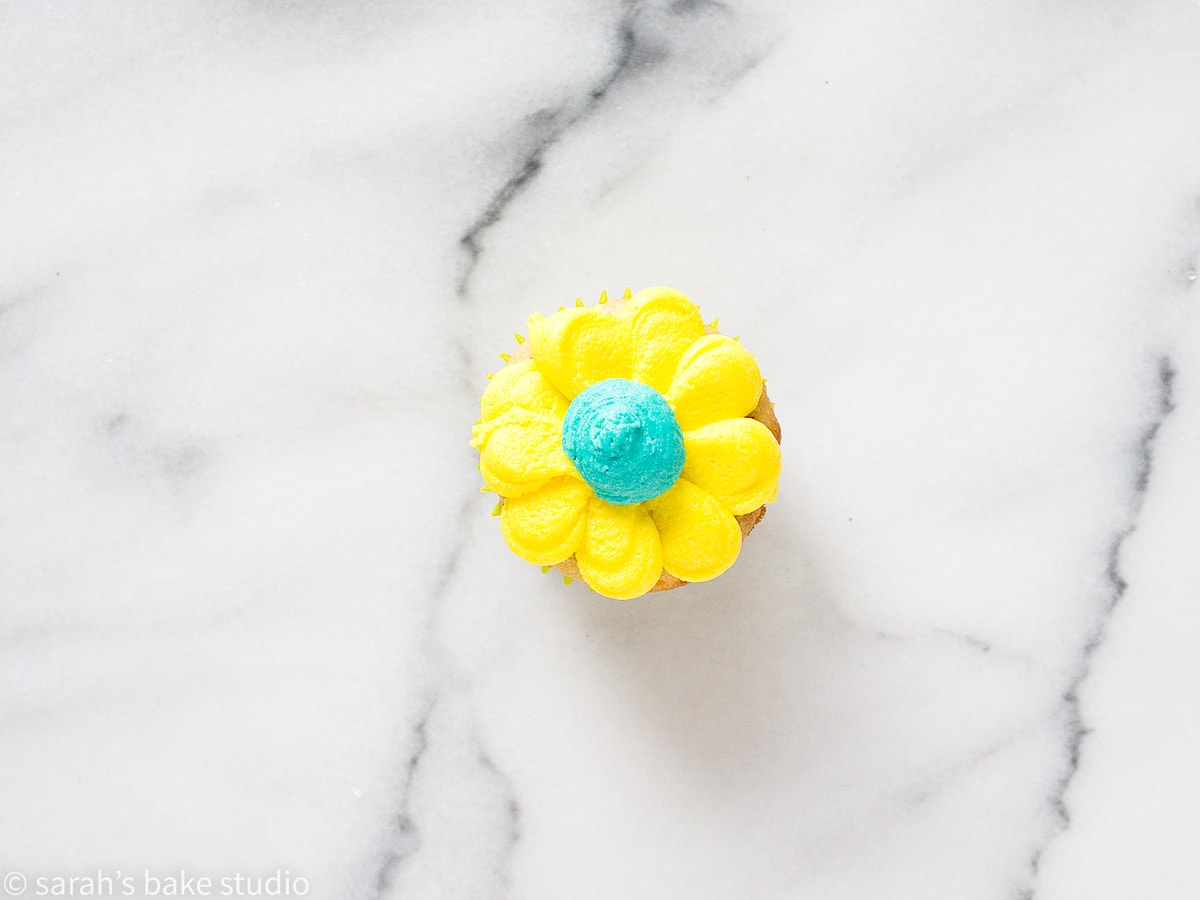 a single mini cupcake with colorful buttercream frosting that resembles a daisy