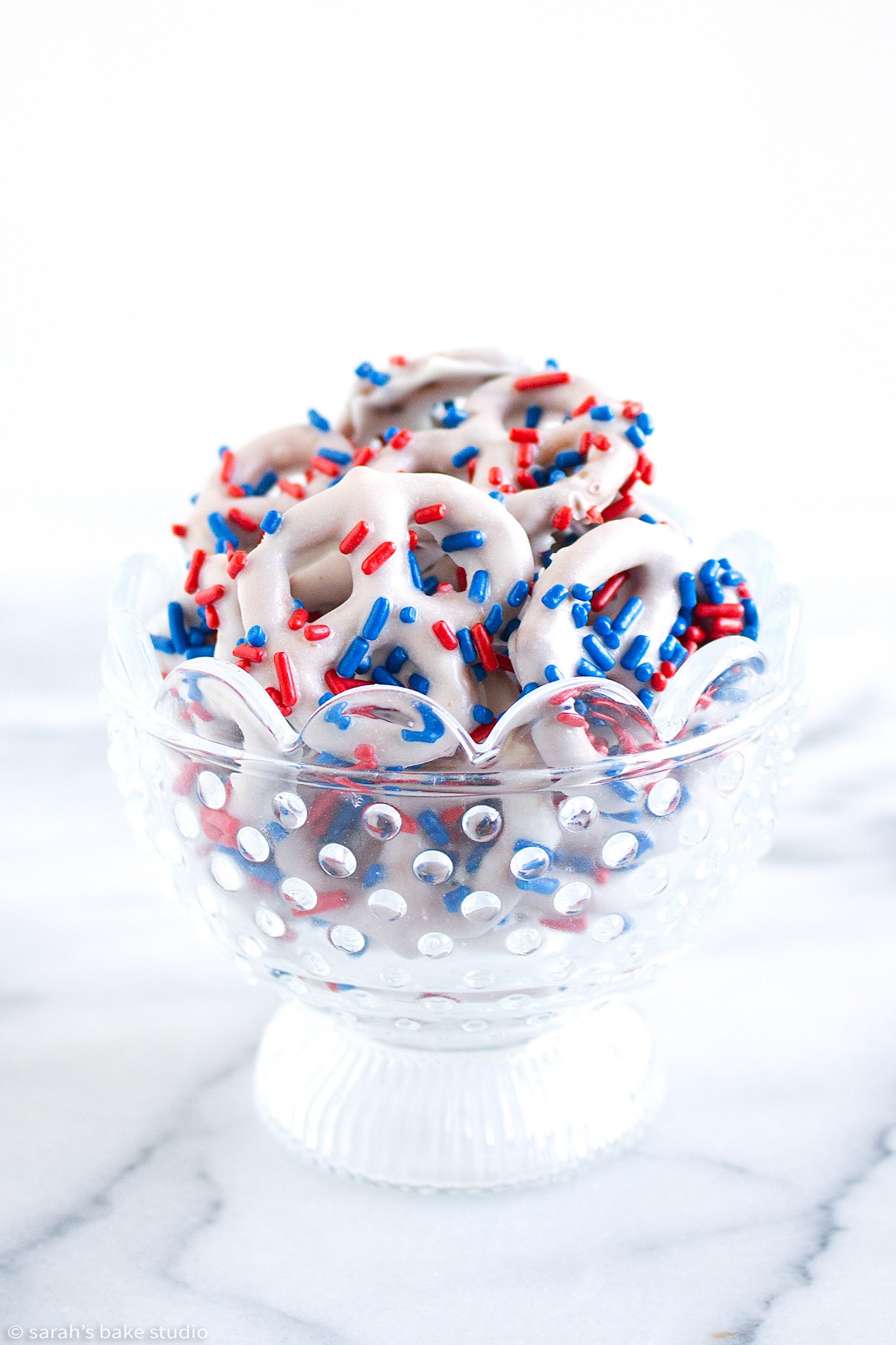 a glass bowl filled with patriotic white chocolate pretzels