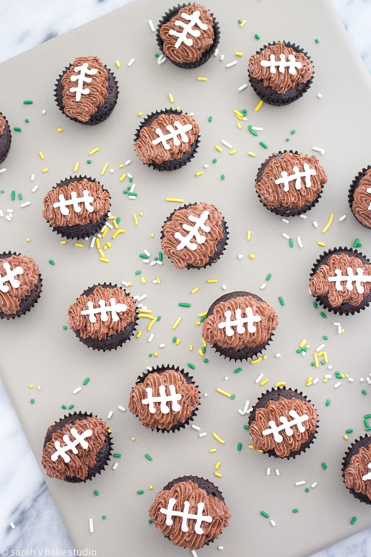 a flatlay of mini football cupcakes with green and yellow sprinkles sprinkled around the cupcakes.
