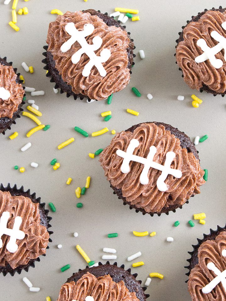 a flatlay of mini football cupcakes with green, yellow, and white sprinkles sprinkled around the cupcakes.