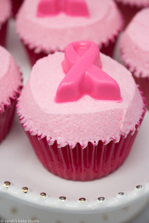 Pink Ribbon Pink Velvet Cupcakes – pink velvet cupcakes crowned with pink buttercream and adorned with white chocolate pink ribbons; a pinkalicous cupcake in honor of Breast Cancer Awareness Month.