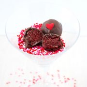 a martini glass filled with valentine's day sprinkles and red velvet oreo truffles.
