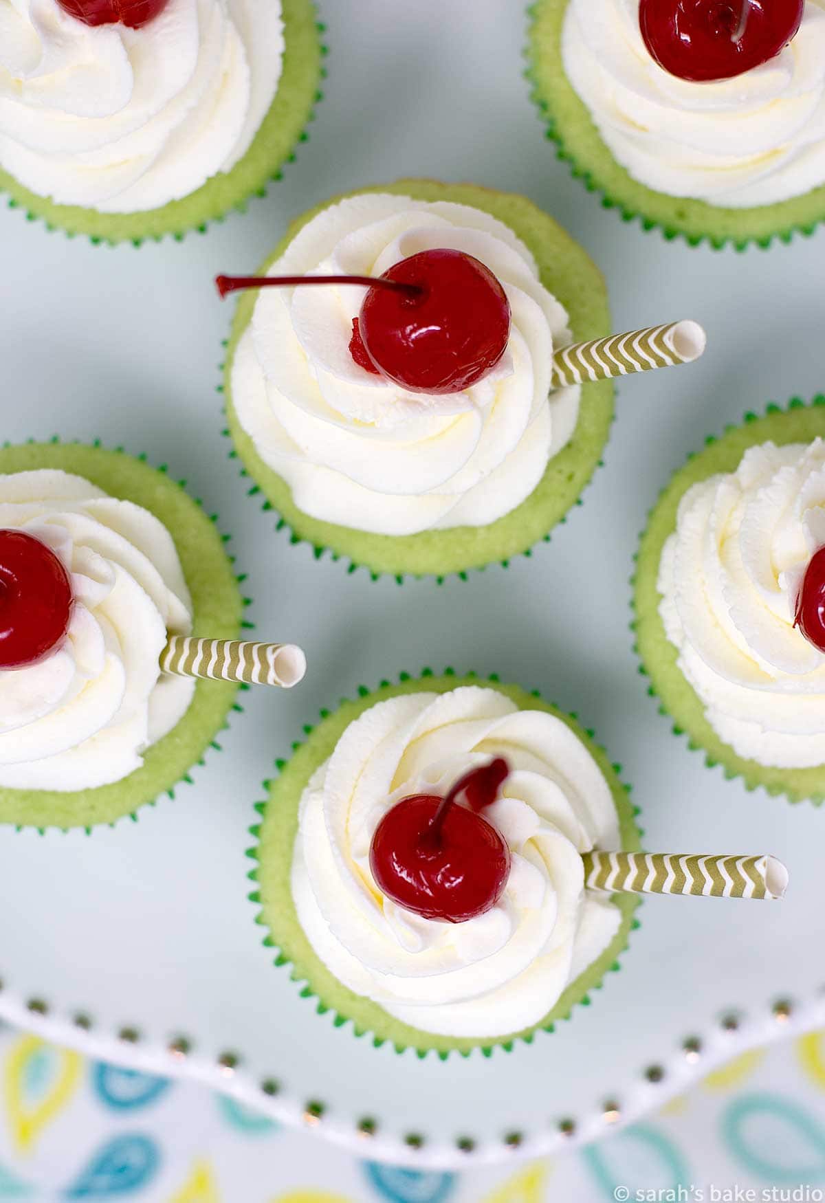 a flatlay of shamrock shake cupcakes making only the whipped cream and cherry visible.