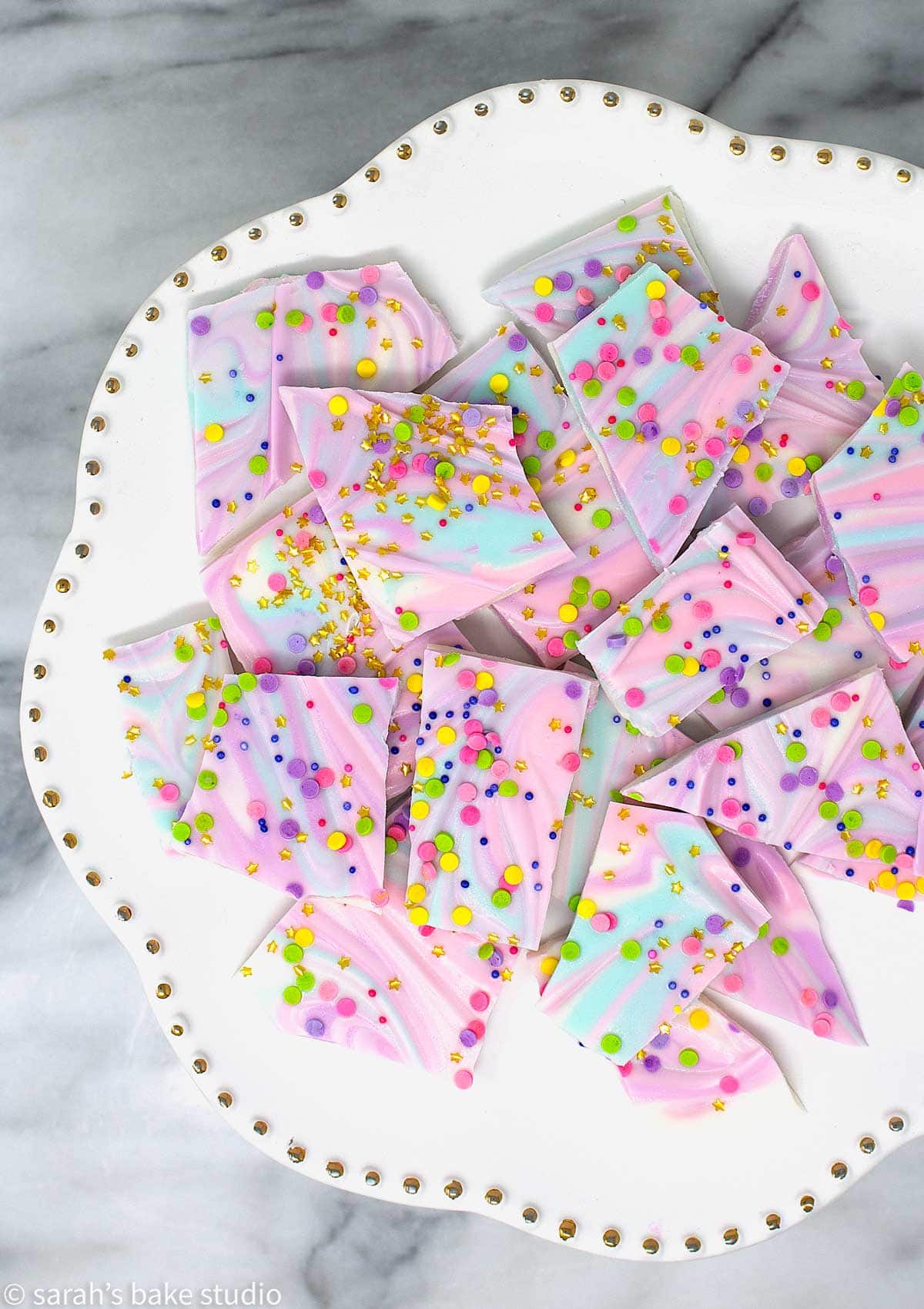 A cake plate stacked with White Chocolate Unicorn Bark.