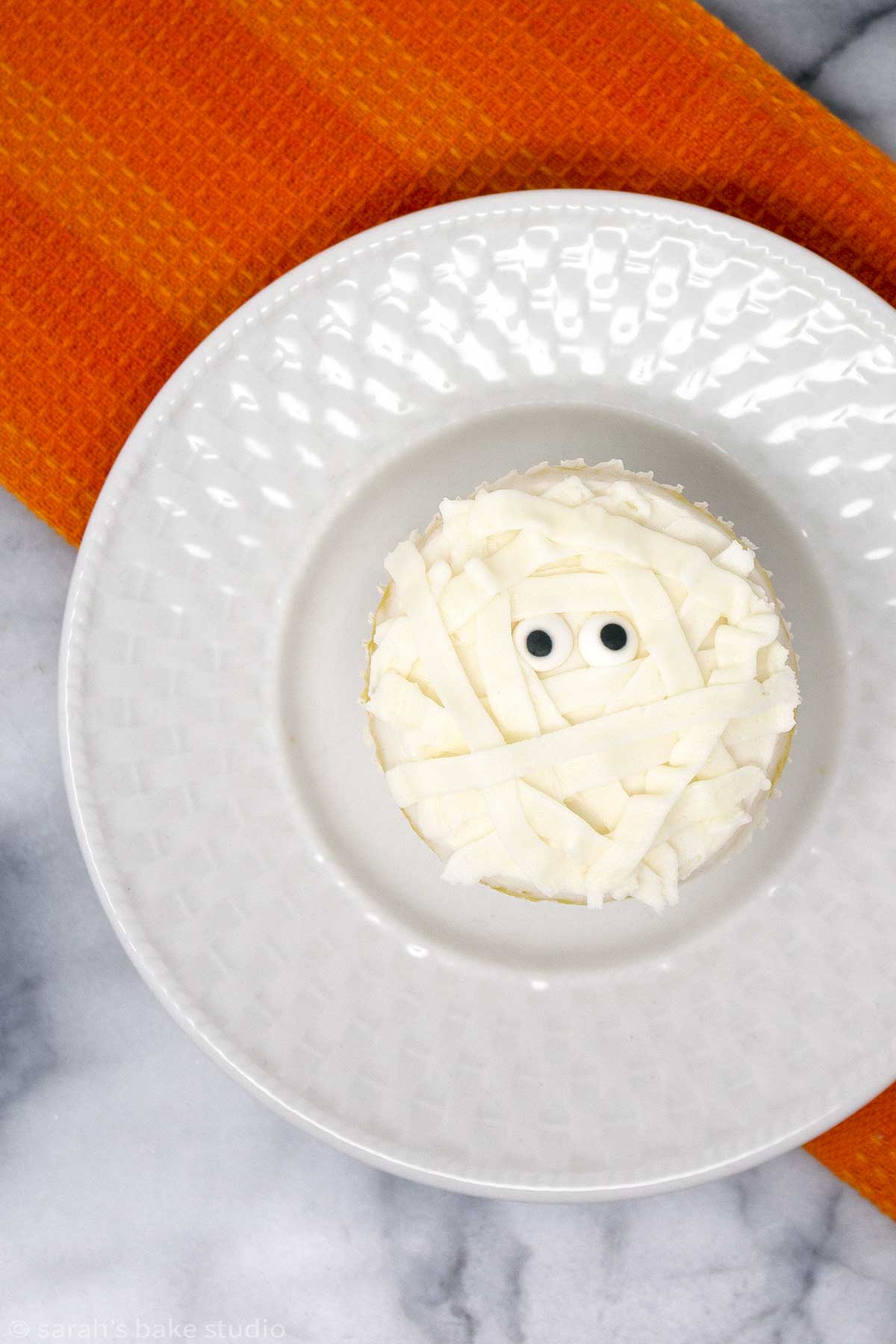 a single halloween mummy cupcake on a white plate.