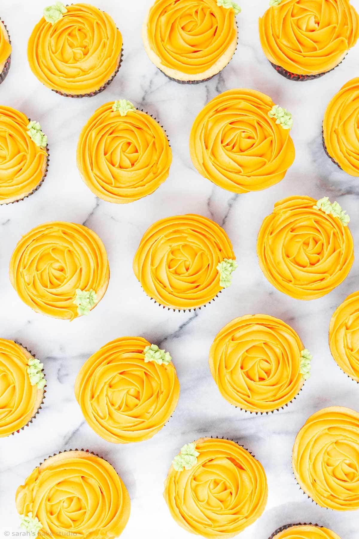 a flatlay of decorated pumpkin cupcakes.